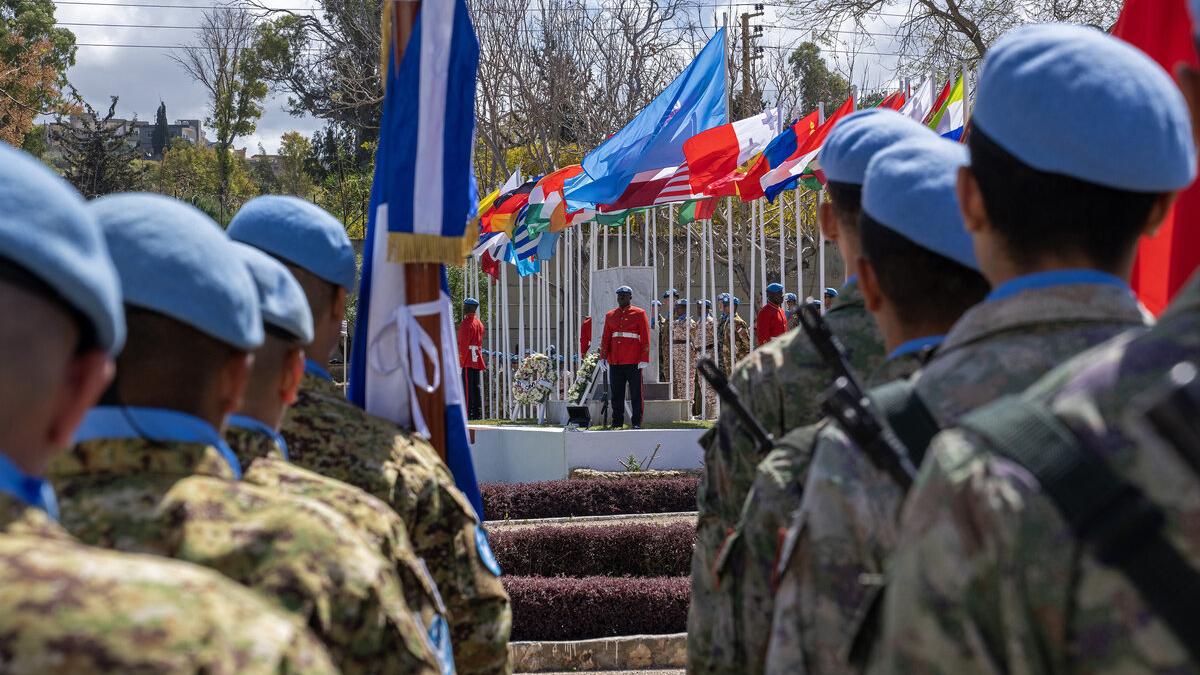 Peacekeepers stand in line and face a stage.