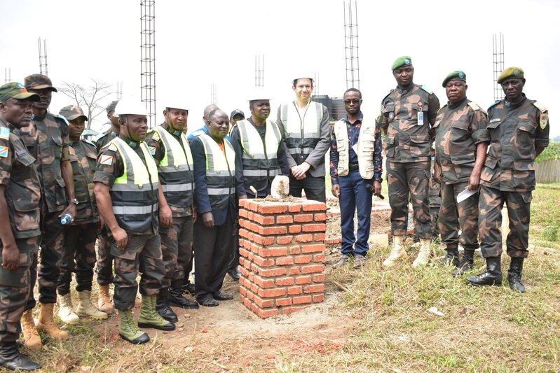Un groupe pose pour une photo à côté d'une structure en briques.